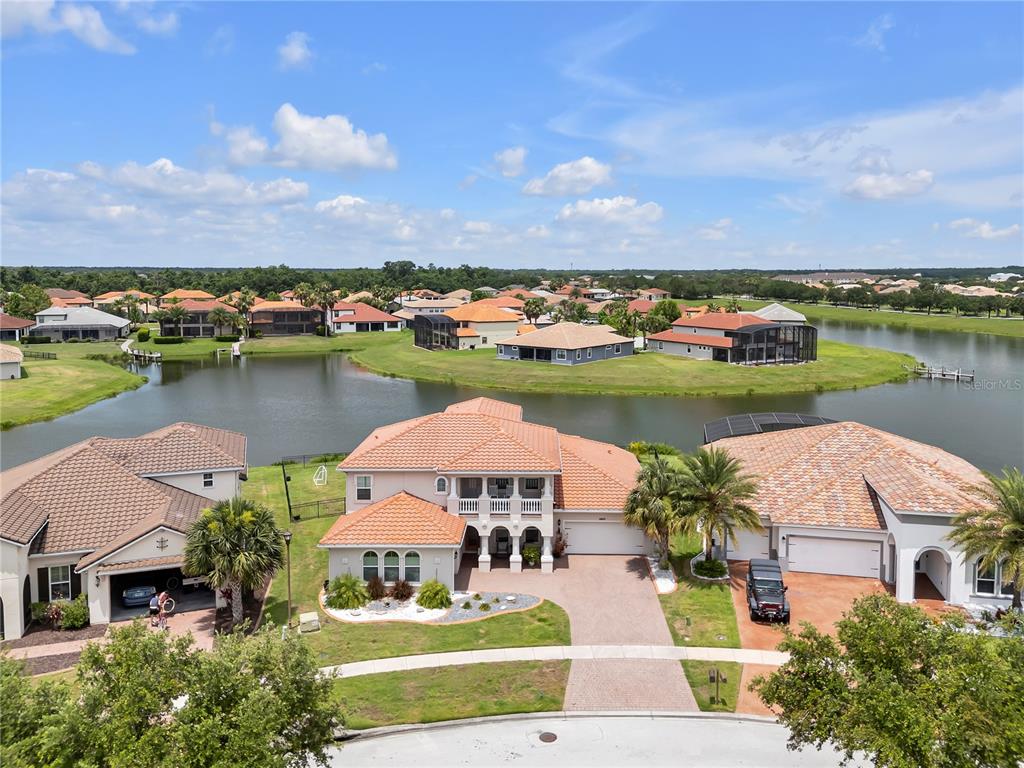 An aerial view shows three suburban houses with tile roofs situated along a waterfront — 3869 SHORESIDE DRIVE, KISSIMMEE, FL