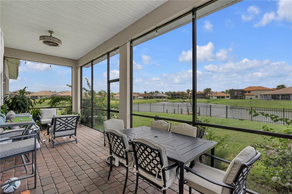 A screened-in patio with outdoor furniture overlooks a grassy lawn, a lake, and neighboring houses — 3869 SHORESIDE DRIVE, KISSIMMEE, FL