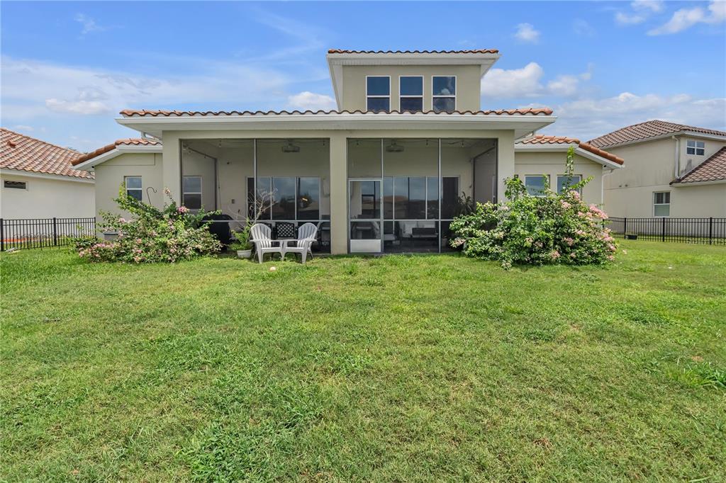 The rear exterior of a house features a screened-in patio, a grassy yard, and fencing — 3869 SHORESIDE DRIVE, KISSIMMEE, FL