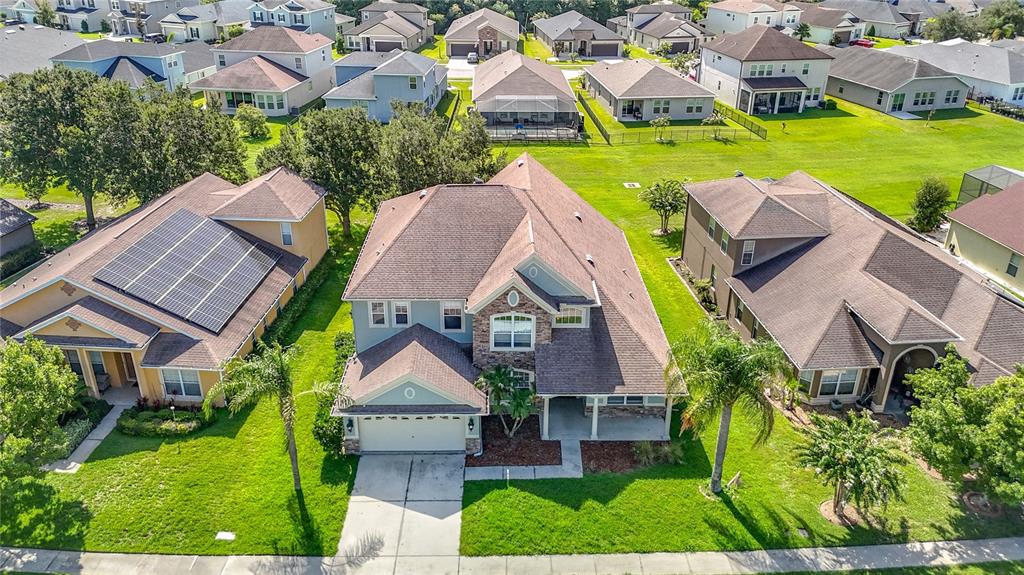 An aerial view of a suburban neighborhood featuring a two-story house with a stone facade — 4736 POINTE O WOODS DRIVE, WESLEY CHAPEL, FL