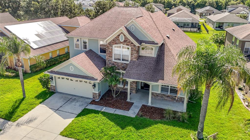 An aerial view of a two-story suburban house with a stone facade and shingled roof — 4736 POINTE O WOODS DRIVE, WESLEY CHAPEL, FL