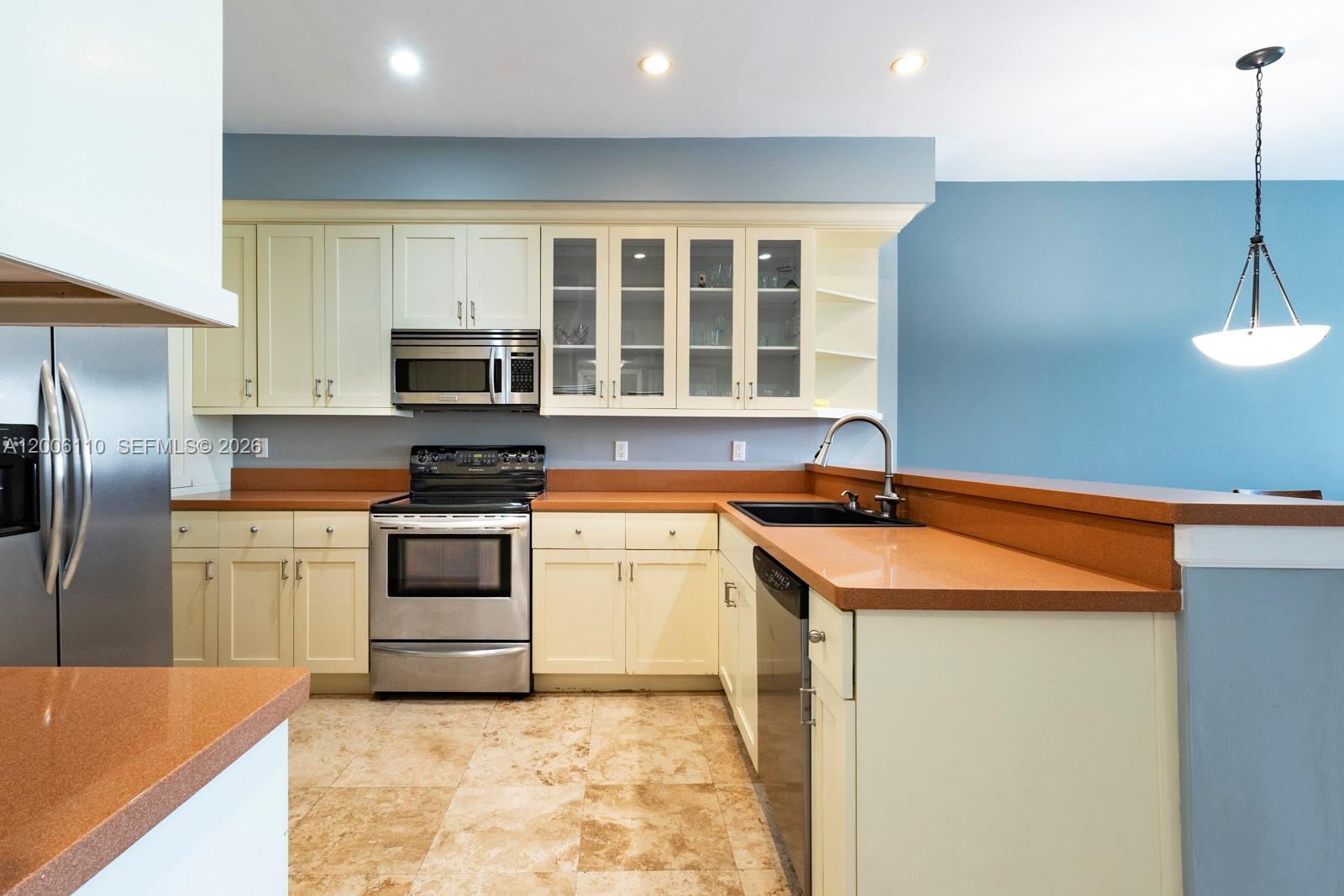 A kitchen features cream cabinets, brown countertops, stainless steel appliances, and light blue walls — 5 Island Ave, Miami Beach FL 33139, MIAMI BEACH, FL
