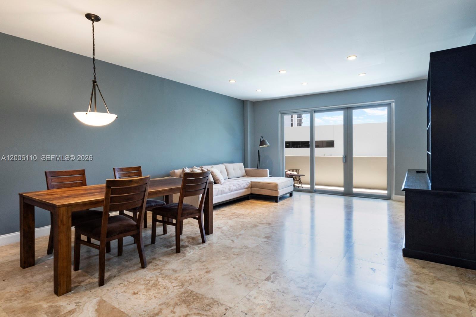A dining and living area features a wooden table, beige sectional sofa, and tile flooring — 5 Island Ave, Miami Beach FL 33139, MIAMI BEACH, FL