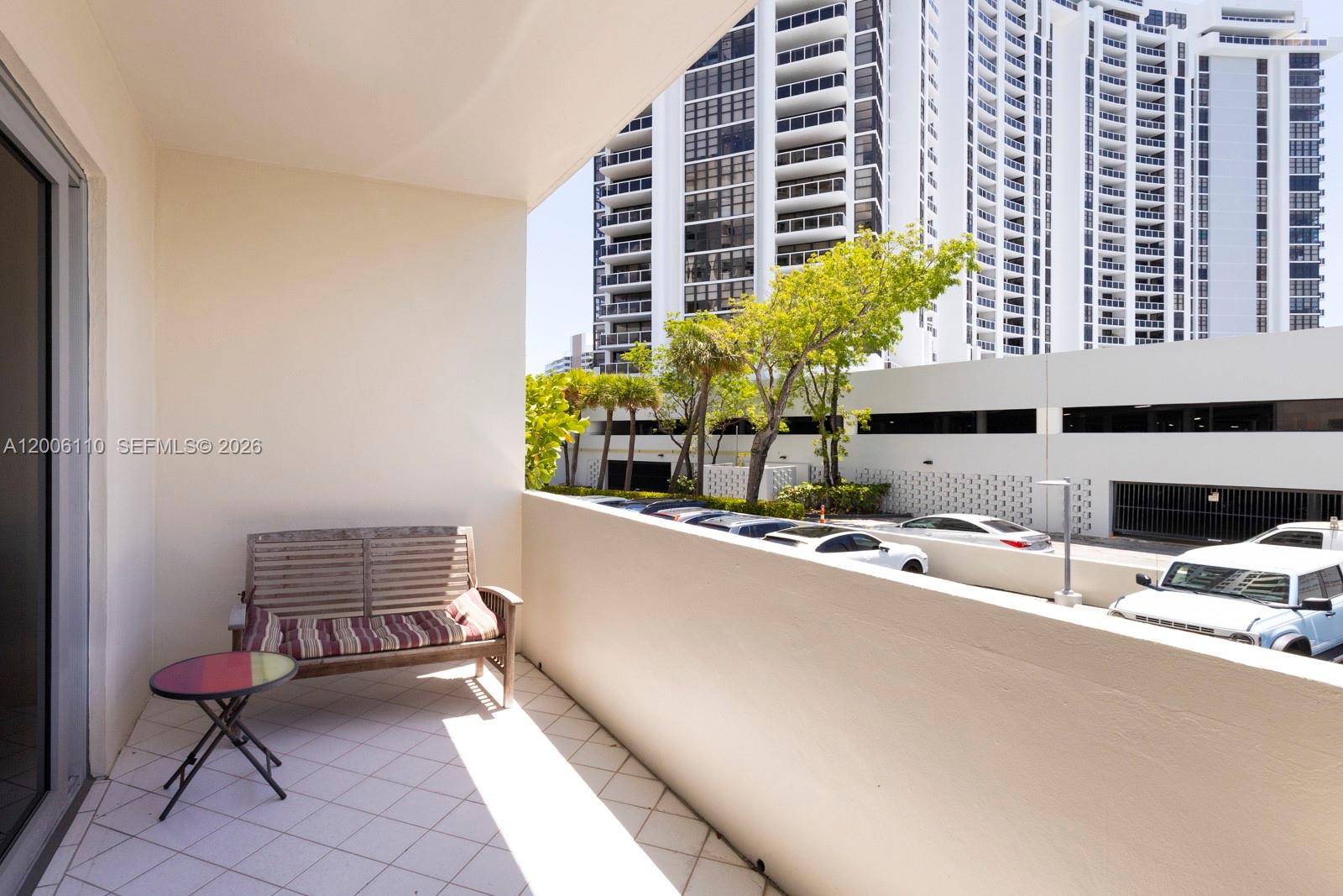 A balcony features a wooden bench, a small round table, and a view of parking — 5 Island Ave, Miami Beach FL 33139, MIAMI BEACH, FL