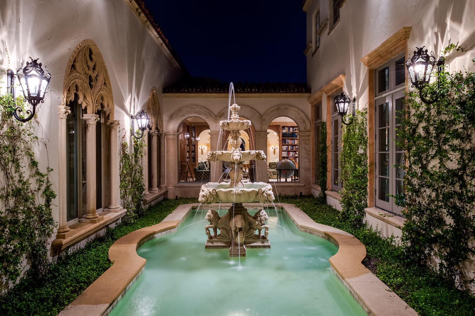 A stone fountain sits in a courtyard pool surrounded by arched windows and climbing vines — 790 S County Road, Palm Beach FL 33480, PALM BEACH, FL