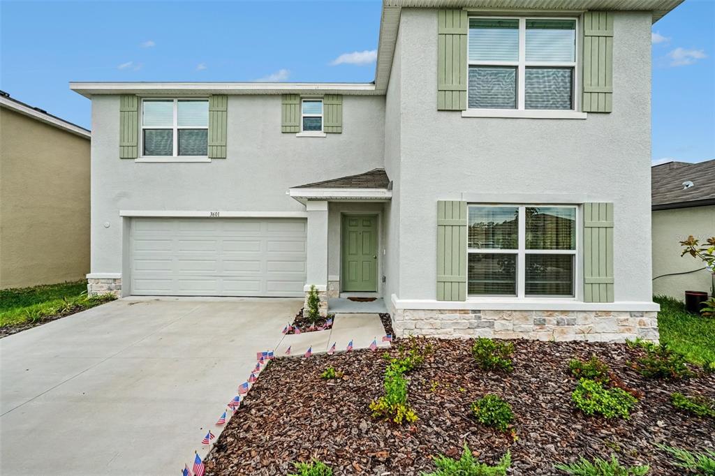 A two-story suburban house with a gray stucco exterior, green shutters, and a concrete driveway — 3601 CAPITAL RESERVE DRIVE, PLANT CITY, FL