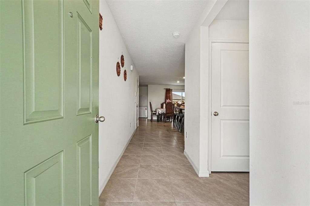 A view from an open green door into a tiled hallway leading to a dining area — 3601 CAPITAL RESERVE DRIVE, PLANT CITY, FL