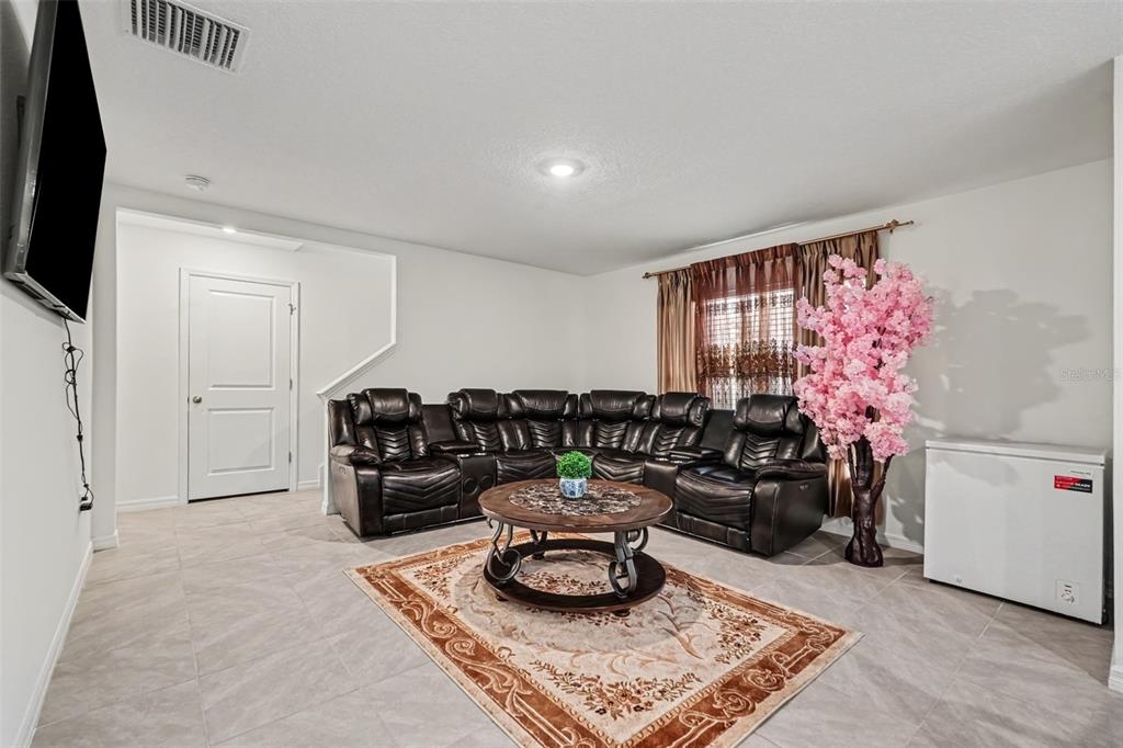 A living room features a large brown sectional sofa, a round coffee table, and tile flooring — 3601 CAPITAL RESERVE DRIVE, PLANT CITY, FL