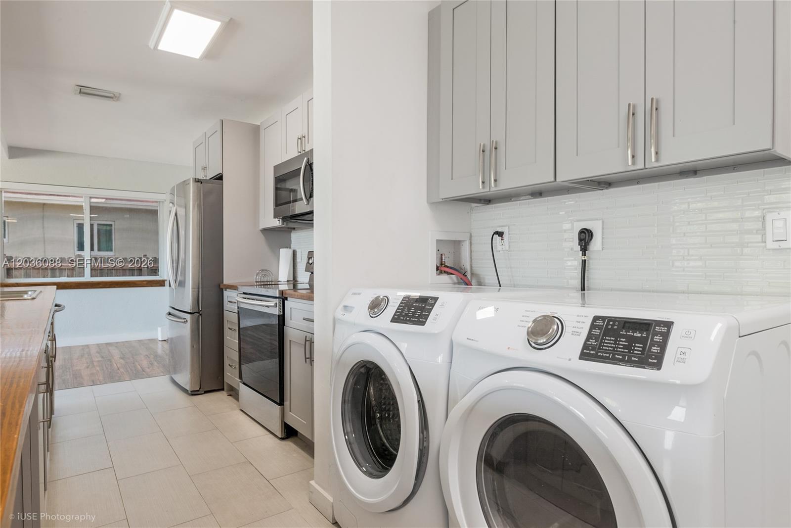 A laundry area with white appliances sits adjacent to a kitchen featuring grey cabinets — 11601 SW 141st St, Miami FL 33176, MIAMI, FL