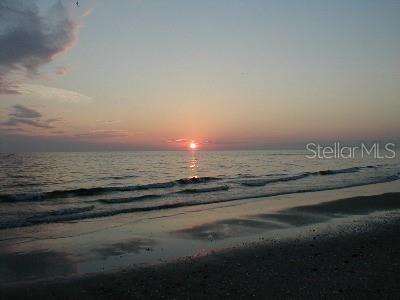 A sunset view over the ocean with waves washing onto a sandy beach — 15009 APPLETON BOULEVARD, PORT CHARLOTTE, FL