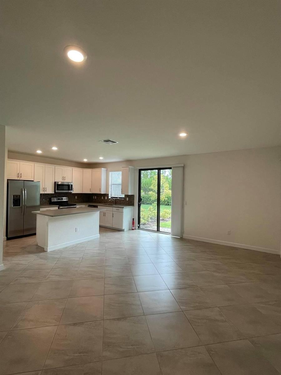 An open-concept kitchen with white cabinets, stainless steel appliances, and tile flooring — 12932 Anthorne Lane, Boynton Beach FL 33436, BOYNTON BEACH, FL