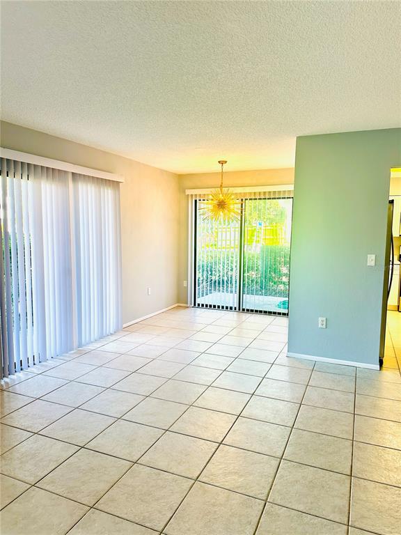A dining area with tile flooring, a starburst chandelier, and sliding glass doors to outside — 2200 BAHIA VISTA ST UNIT B3, SARASOTA, FL