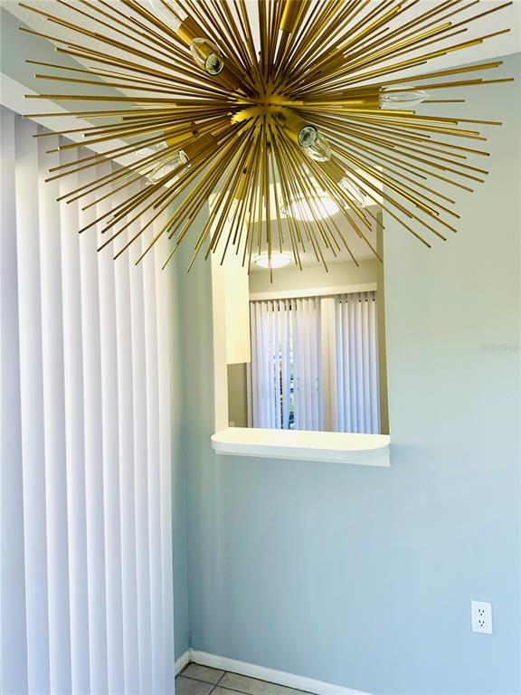 A room with light blue walls, a gold starburst chandelier, and a kitchen pass-through window — 2200 BAHIA VISTA ST UNIT B3, SARASOTA, FL