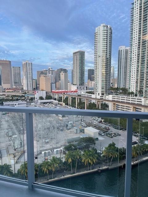 An elevated view from a balcony overlooks a city skyline, a power substation, and a waterway — 185 SW 7th St # 1605, Miami FL 33130, MIAMI, FL