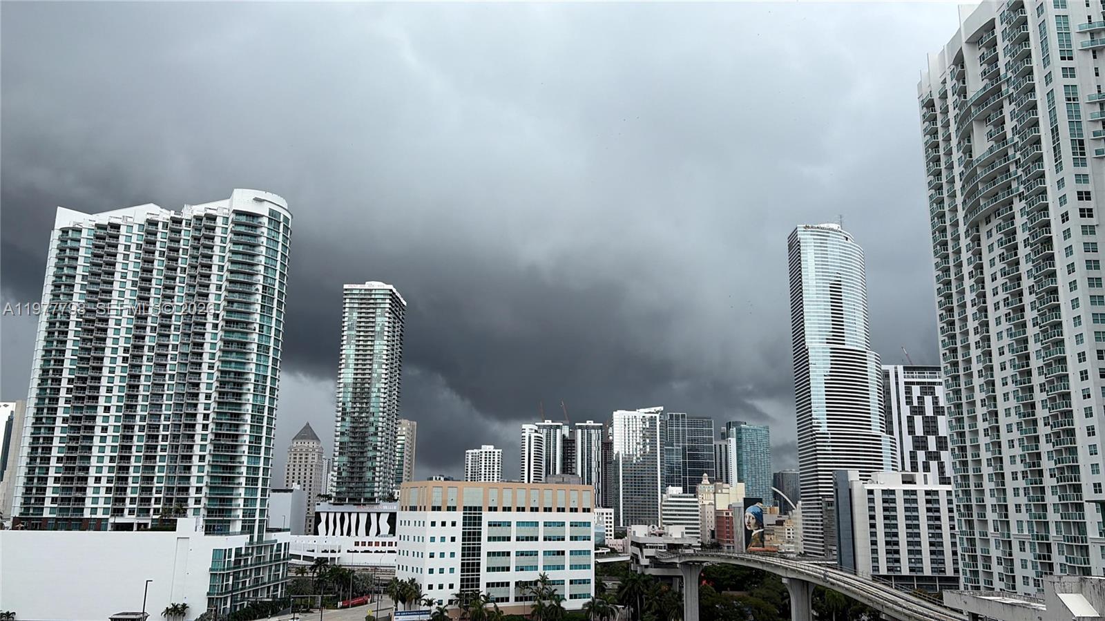 An elevated view of a city skyline featuring several tall skyscrapers under a stormy sky — 185 SW 7th St # 1605, Miami FL 33130, MIAMI, FL