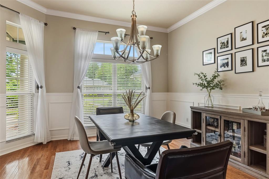 A dining room features a dark wood table, chandelier, sideboard, and a gallery wall — 3782 SW 105TH STREET, GAINESVILLE, FL
