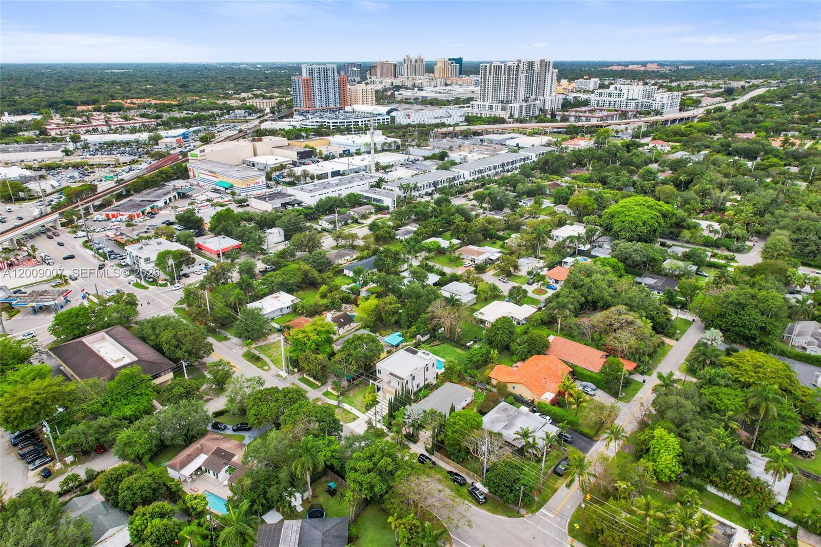 An aerial view shows a suburban neighborhood with houses, trees, and distant city high-rises — 7840 SW 67th Ave, South Miami FL 33143, SOUTH MIAMI, FL