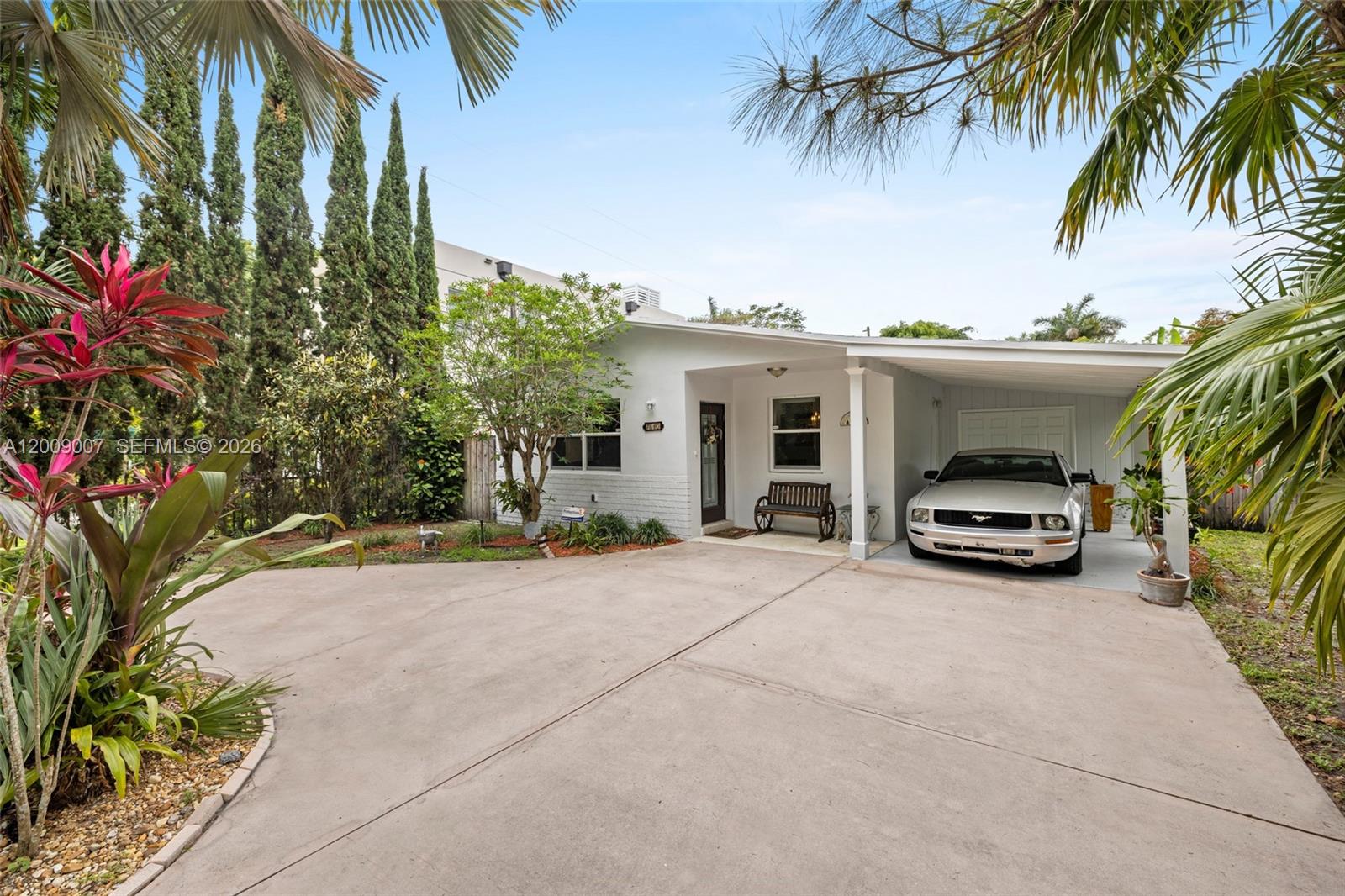 A single-story house with a white exterior, a front porch, and a carport with a car — 7840 SW 67th Ave, South Miami FL 33143, SOUTH MIAMI, FL