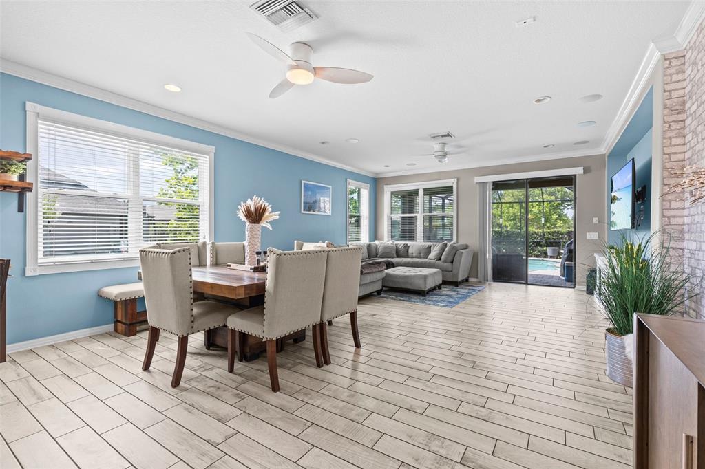 A kitchen with brown cabinets and a stone-topped island opens into a dining and living area — 13353 BATTEN LANE, ODESSA, FL