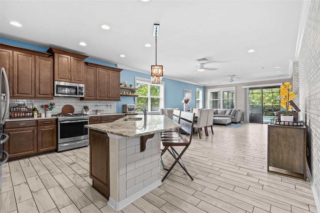 An open-concept living and dining area features light blue walls, wood-look tile, and grey furniture — 13353 BATTEN LANE, ODESSA, FL