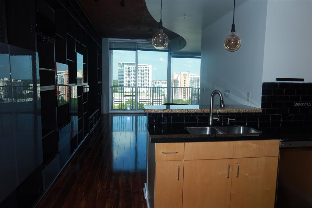 A kitchen with light wood cabinets and black countertops overlooks a balcony with city views — 155 S COURT AVENUE UNIT 1113, ORLANDO, FL
