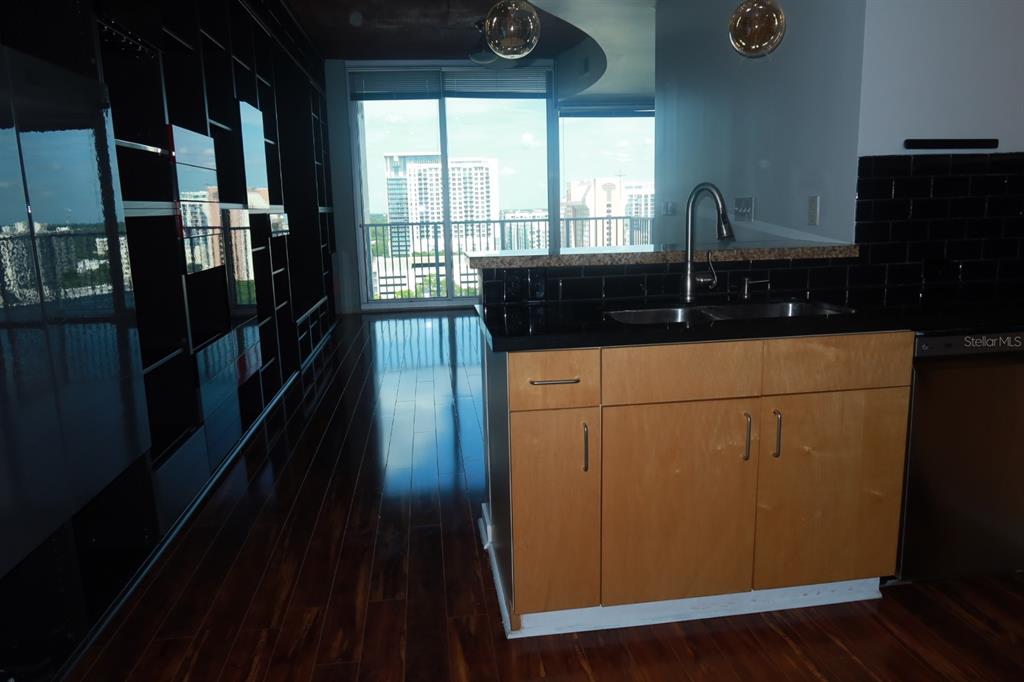 A kitchen island with light wood cabinets and a dark countertop faces a balcony view — 155 S COURT AVENUE UNIT 1113, ORLANDO, FL