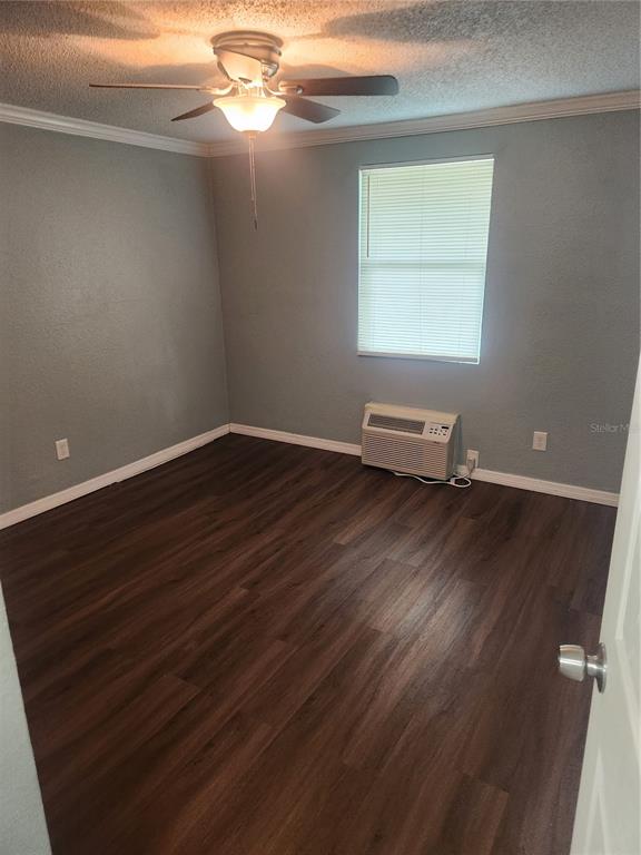 An empty bedroom with gray walls, dark wood-look flooring, a ceiling fan, and a window unit — 5901 BRYCE LANE UNIT 5903, TAMPA, FL