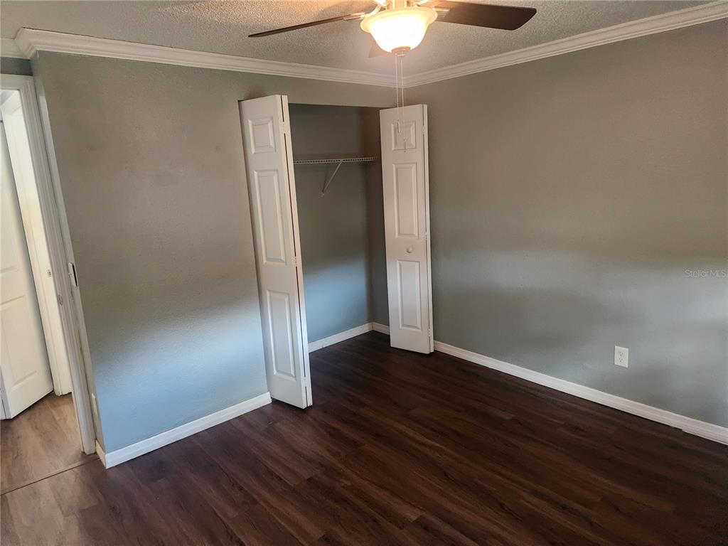A bedroom with gray walls, dark wood-look flooring, a ceiling fan, and an open closet — 5901 BRYCE LANE UNIT 5903, TAMPA, FL