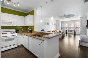 A kitchen with white cabinets and green walls opens into a living and dining area — 2732 VIA MURANO UNIT 534, CLEARWATER, FL
