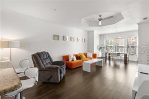 A living room features dark wood flooring, an orange sofa, and a gray recliner — 2732 VIA MURANO UNIT 534, CLEARWATER, FL