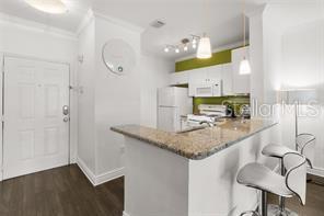A kitchen with white cabinets, granite countertops, and a breakfast bar with two stools — 2732 VIA MURANO UNIT 534, CLEARWATER, FL