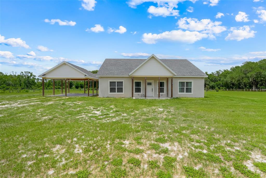 A single-story house with a carport sits on a large, grassy, open lot — 21301 QUAIL HAMMOCK LANE, GROVELAND, FL