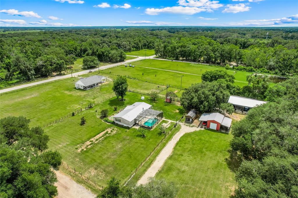 An aerial view shows a house and outbuildings on a large, fenced rural property — 21301 QUAIL HAMMOCK LANE, GROVELAND, FL