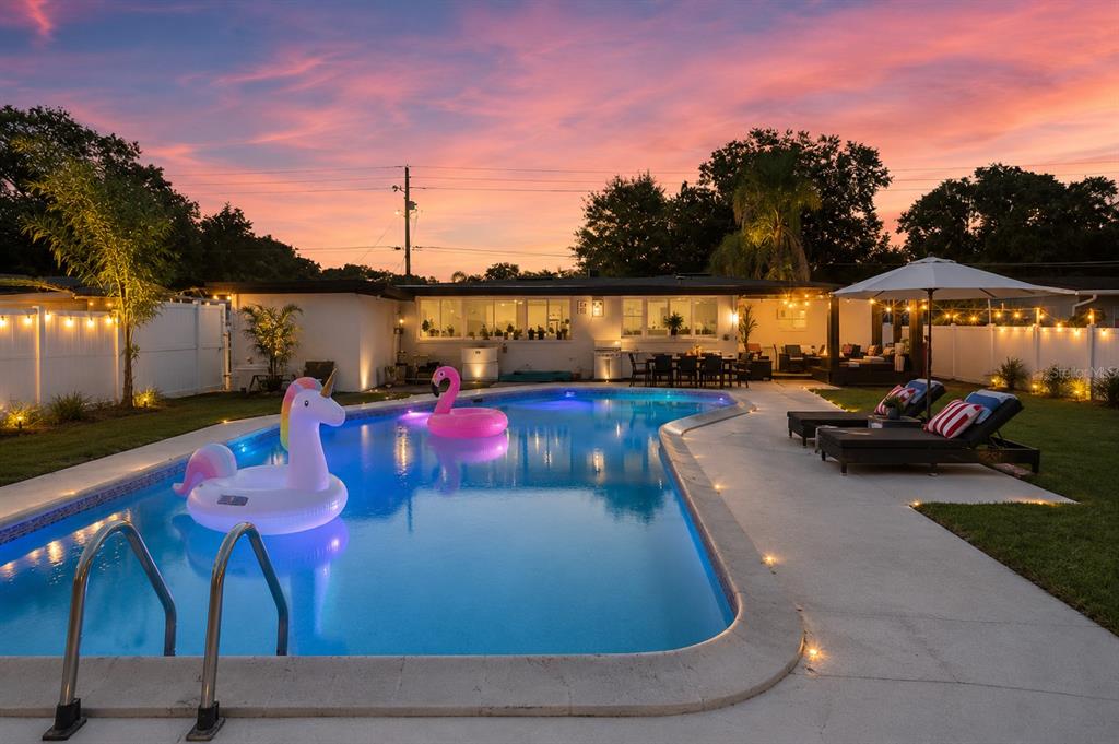A backyard swimming pool with inflatable floats at sunset, featuring a patio and house exterior — 8120 GONDOLA DRIVE, ORLANDO, FL