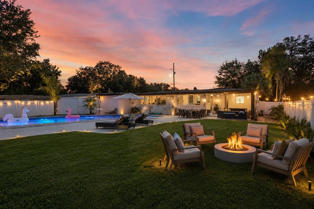A backyard at sunset features a swimming pool, a fire pit, and patio seating — 8120 GONDOLA DRIVE, ORLANDO, FL