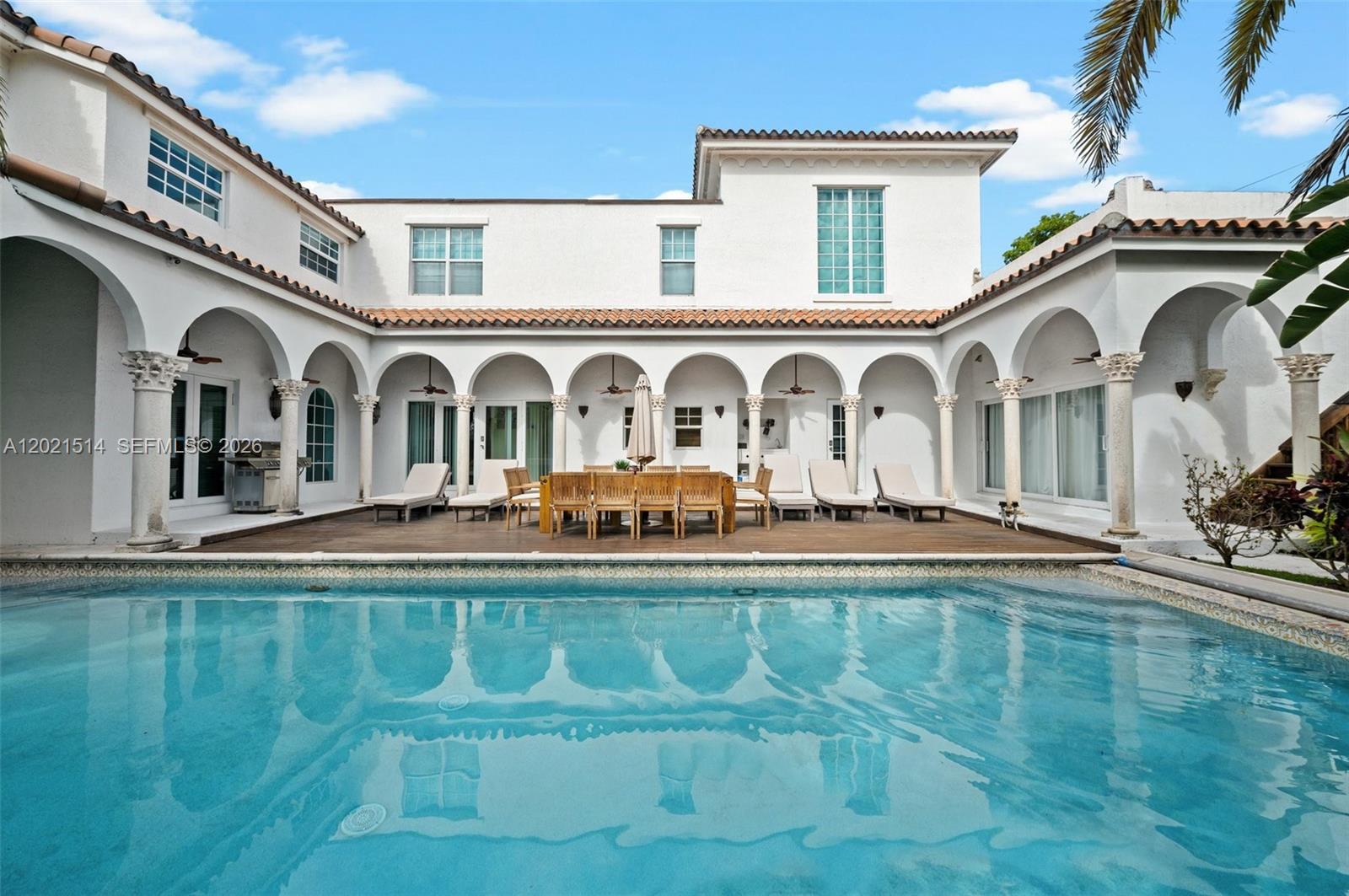 A white Mediterranean-style house features a large swimming pool and a covered patio area — 2501 Pine Tree Dr, Miami Beach FL 33140, MIAMI BEACH, FL
