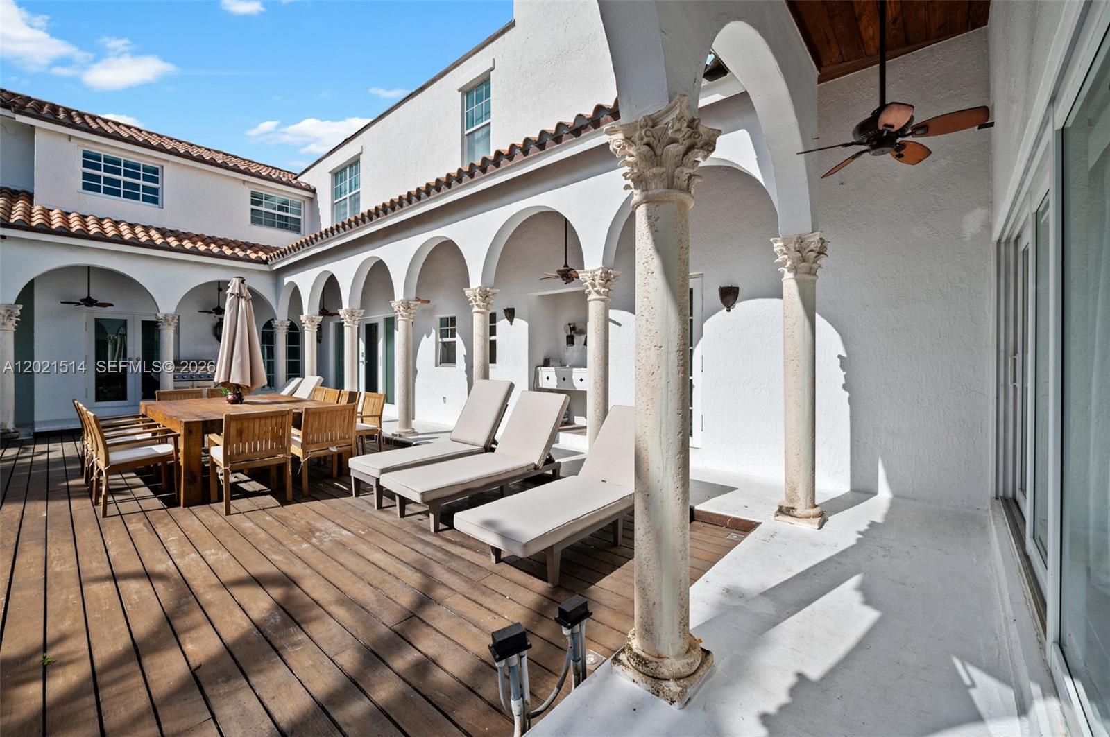 A wooden deck features a dining set and lounge chairs under a covered arched patio — 2501 Pine Tree Dr, Miami Beach FL 33140, MIAMI BEACH, FL
