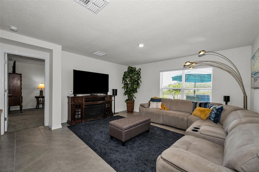 A living room features a large sectional sofa, a television on a console, and tile flooring — 13469 MYLION WAY, SPRING HILL, FL