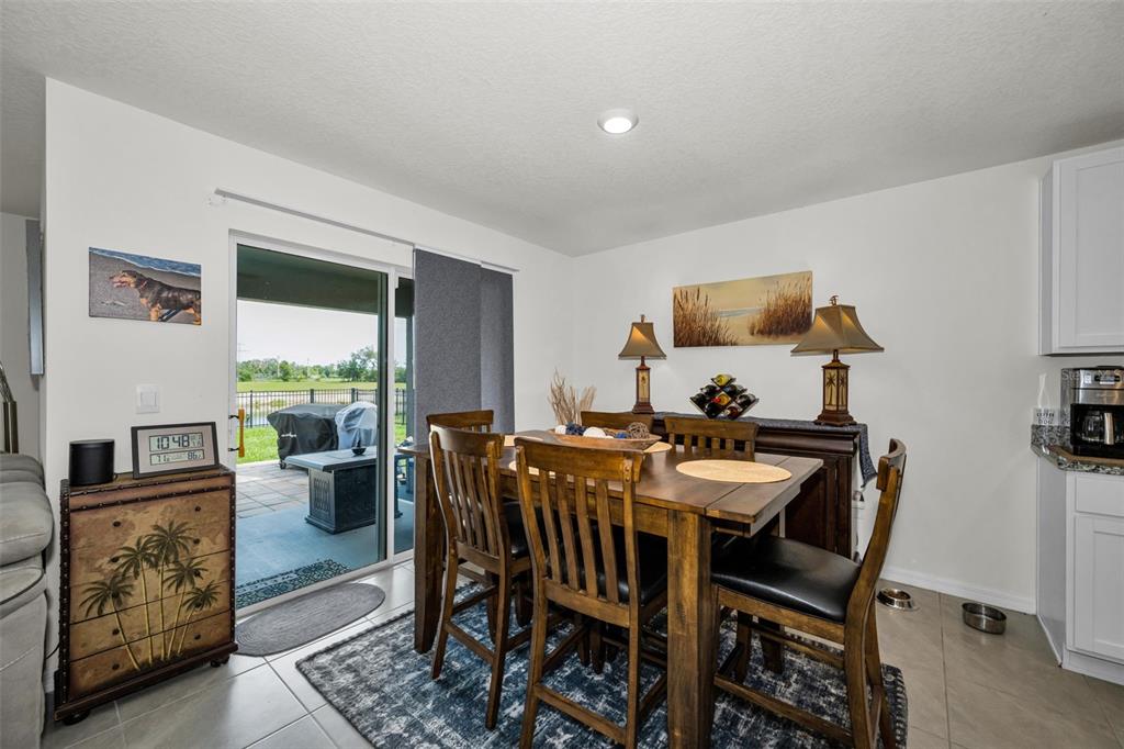 A dining area features a wooden table, chairs, a sideboard, and a sliding glass door — 13469 MYLION WAY, SPRING HILL, FL