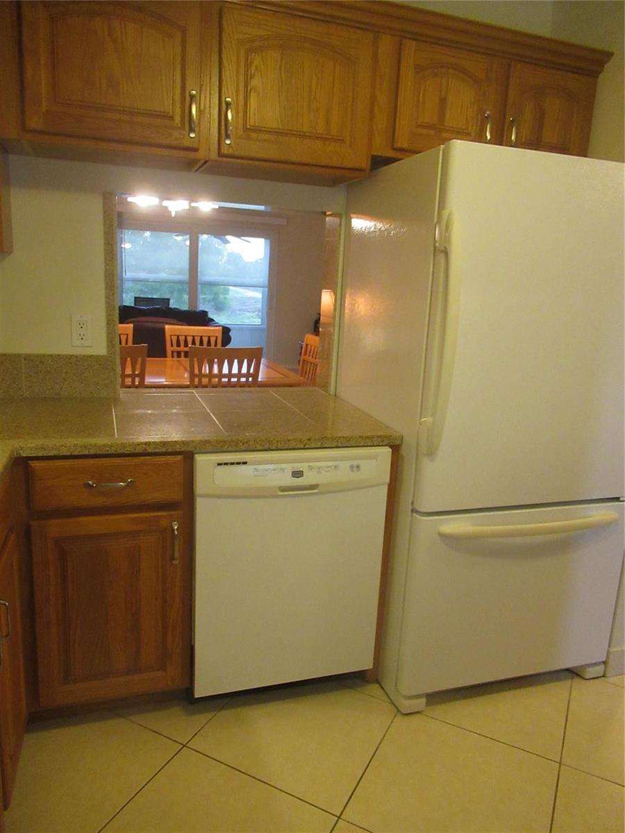 A kitchen features oak cabinets, granite countertops, white appliances, and a window with blinds — 601 NW 76th Terrace # 206, Margate FL 33063, MARGATE, FL
