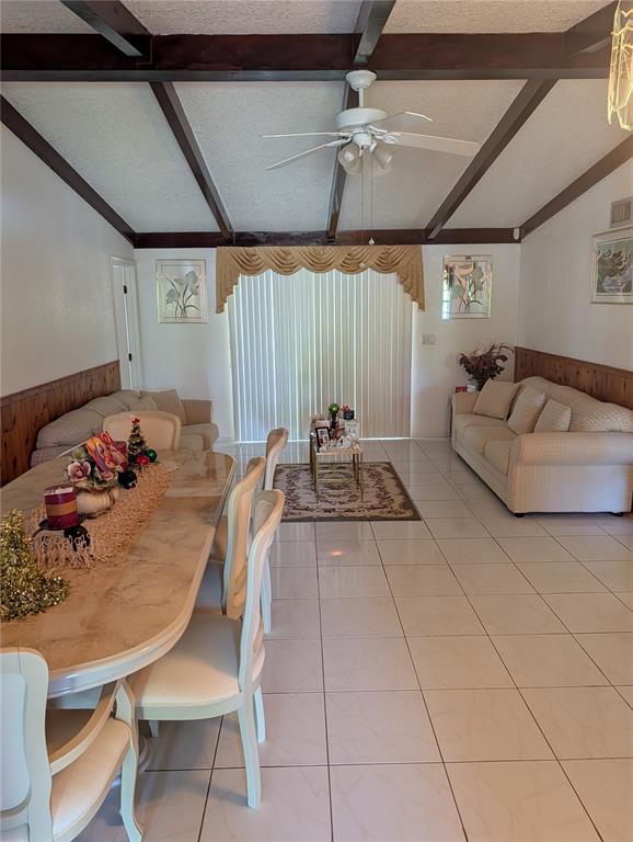 A dining area and living room with vaulted ceilings, exposed beams, and tile flooring — 3280 GLENCOVE STREET, PUNTA GORDA, FL