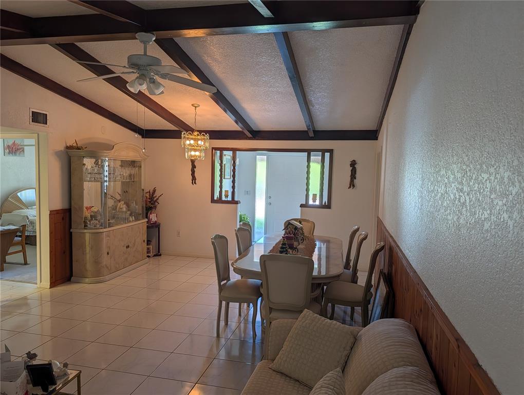 A dining room features a vaulted ceiling with exposed beams, tile flooring, and wainscoting — 3280 GLENCOVE STREET, PUNTA GORDA, FL