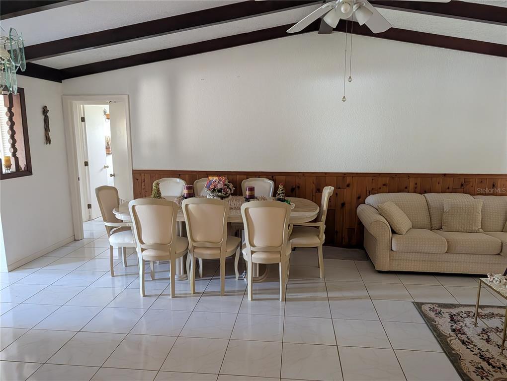 A dining area with a table and chairs sits before a wood-paneled wall — 3280 GLENCOVE STREET, PUNTA GORDA, FL