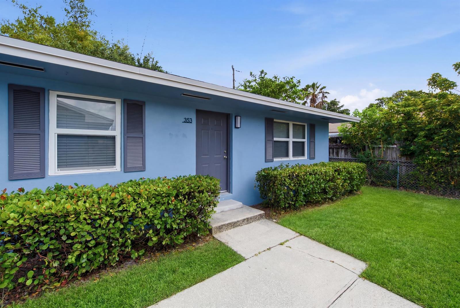 A light blue house exterior features a grey front door, shutters, and a front lawn — 353 Wickline Boulevard, Lantana FL 33462, LANTANA, FL