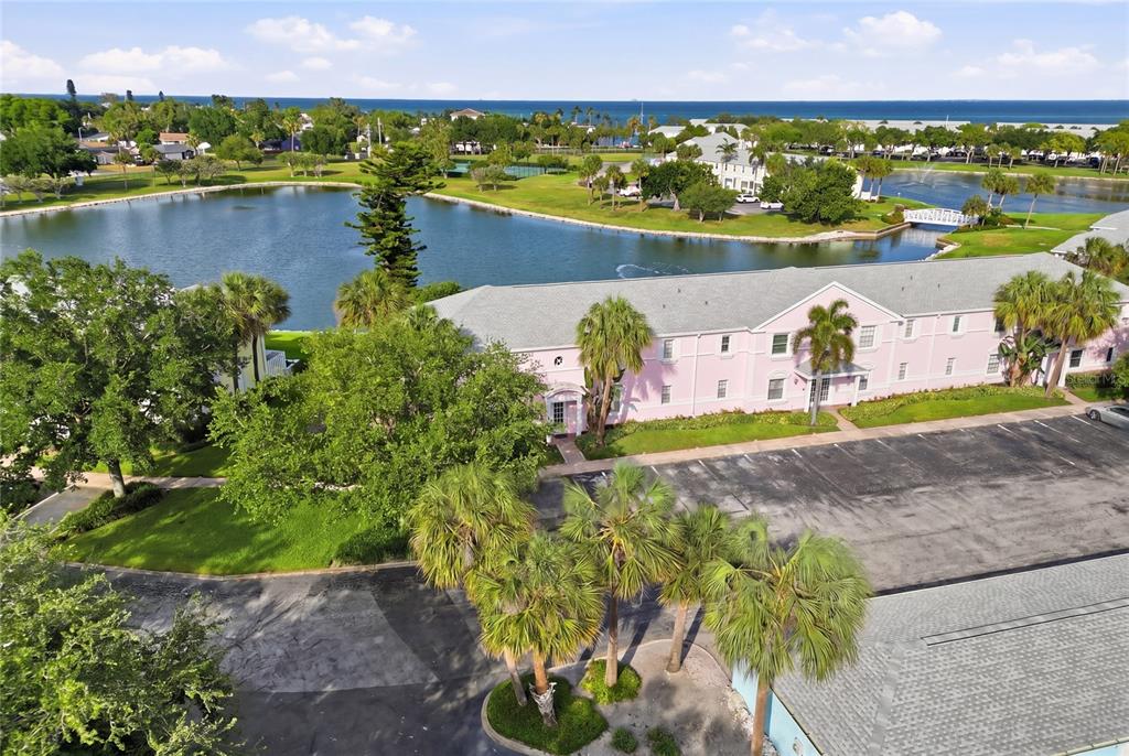 An aerial view shows a pink multi-story building situated beside a lake and parking lot — 4754 COBIA DRIVE SE UNIT D, ST PETERSBURG, FL
