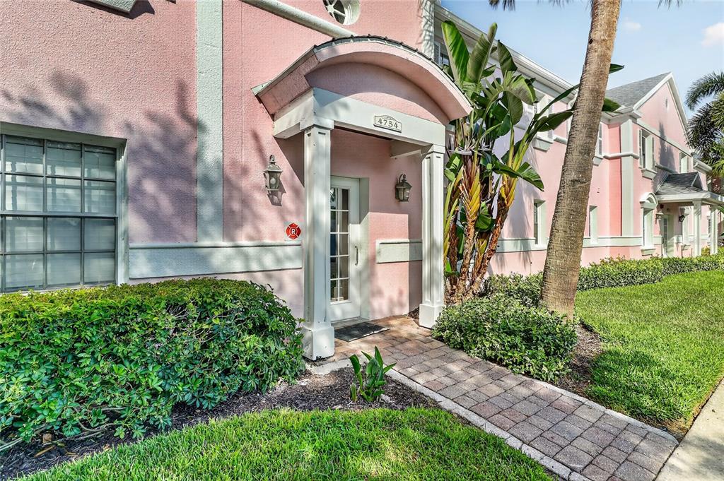 A pink stucco building exterior features a covered entryway with a brick walkway — 4754 COBIA DRIVE SE UNIT D, ST PETERSBURG, FL