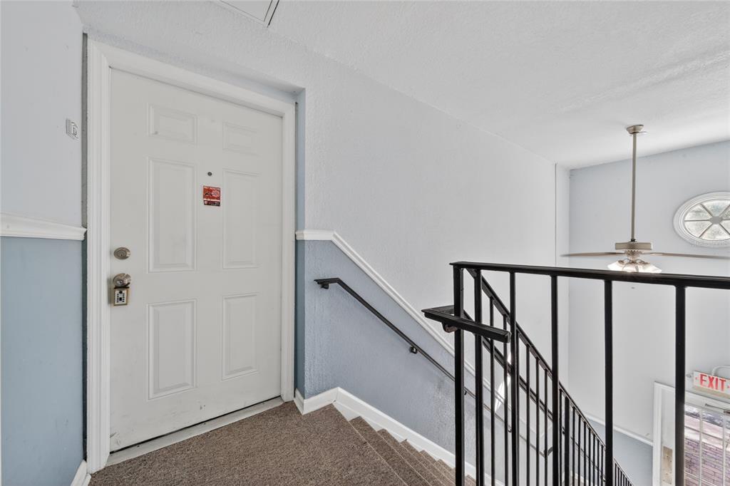 A white entry door sits at the top of carpeted stairs with a black railing — 4754 COBIA DRIVE SE UNIT D, ST PETERSBURG, FL