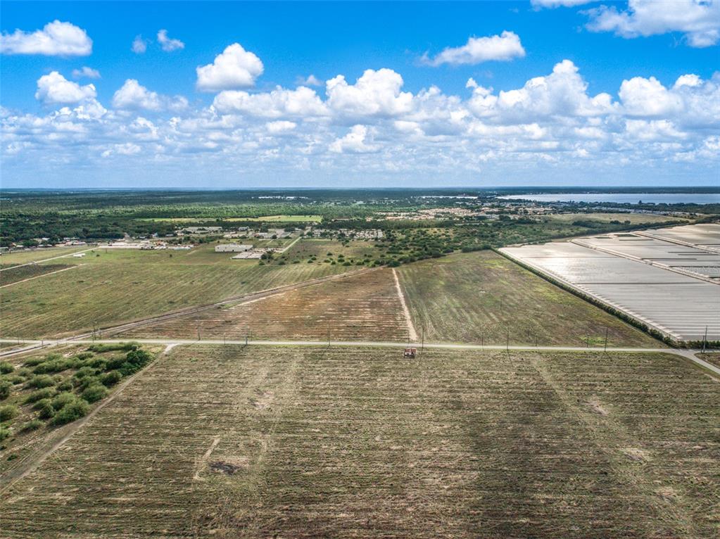 An aerial view shows a large, flat, undeveloped grassy lot bordered by a road — 4199 DESOTO CITY ROAD, SEBRING, FL