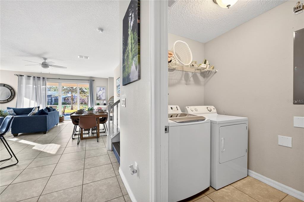 A laundry room with a washer and dryer sits beside an open-concept living and dining area — 4787 TERRASONESTA DRIVE, DAVENPORT, FL