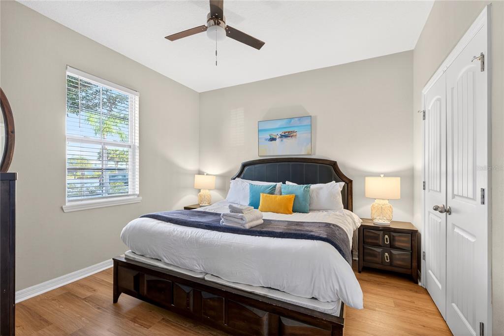 A bedroom features a dark wood bed frame, two nightstands with lamps, and wood flooring — 4787 TERRASONESTA DRIVE, DAVENPORT, FL